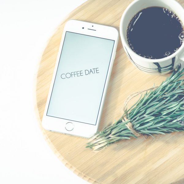 lavender and mug of coffee on small table near iphone